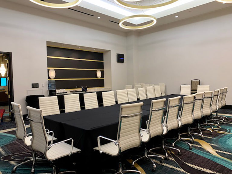 Professional meeting room with executive style office furniture including 15' conference table with charging stations and 18 white executive chairs