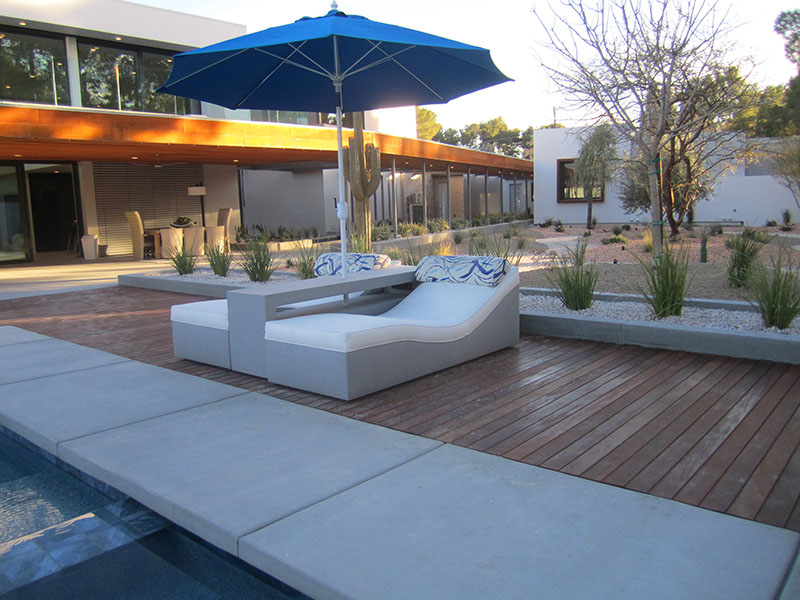 Custom white and grey adjustable loungers with a charging side table and umbrella poolside at luxury residence