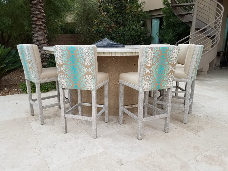 Tall barstools with cushioned seats and backs and fabric wrapped bases surround a round fire pit