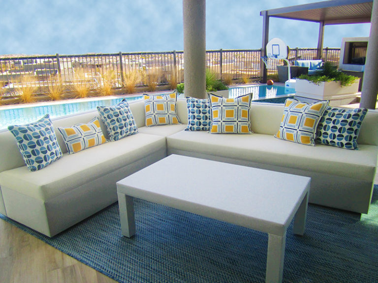 custom sized tightseated white and gray upholstered sectional accented with blue and yellow textured pillows and gray rectangle cocktail table outdoor fabric wrapped for durable and carefree living outside in Las Vegas
